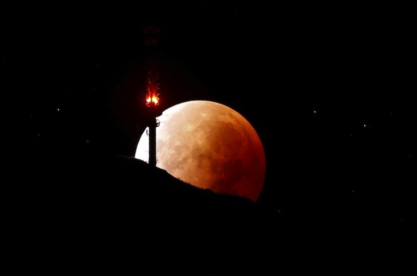 The moon, appearing in a dim red colour, is covered by the Earth's shadow during a total lunar eclipse over the peak of mount Rigi, Switzerland, September 28, 2015. Sky-watchers around the world were treated when the shadow of Earth cast a reddish glow on the moon, the result of rare combination of an eclipse with the closest full moon of the year. The total "supermoon" lunar eclipse, also known as a "blood moon" is one that appears bigger and brighter than usual as it reaches the point in its orbit that is closest to Earth. REUTERS/Arnd Wiegmann    Picture Supplied by Action Images - MT1ACI14036703